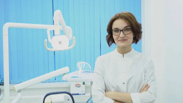 Mujer dentista se encuentra con el cliente sonriendo. Medios. Mujer dentista en bata blanca da la bienvenida a un nuevo cliente en el consultorio dental. Concepto dental —  Fotos de Stock