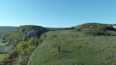 Mavi gökyüzünün altında tepenin üstüne yürüyen adam. Vurdu. Üstten harika görünüm