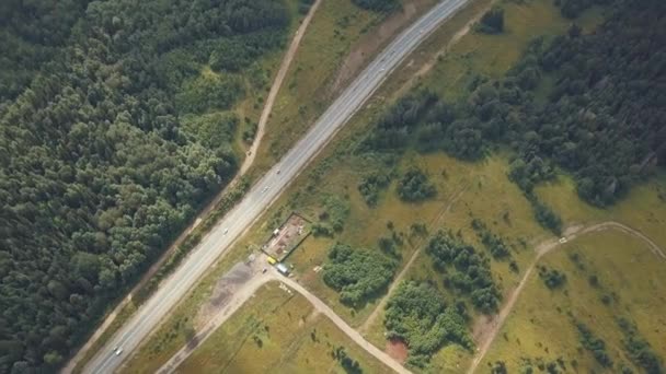 Vista aérea de la carretera con coches en movimiento. Clip. Camino a través de los campos y el bosque — Vídeo de stock
