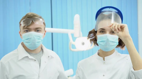 Muž a žena zubařů v maskách a brýle. Média. Partneři zubařů v ochranné sterilní uniformě s výstrojí se dostat do práce — Stock fotografie
