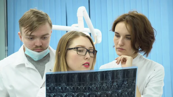 Equipa de médicos a ver imagens de ressonância magnética. Mídia. Médicos de uniforme branco assistindo RM e compartilham opiniões sobre diagnóstico — Fotografia de Stock