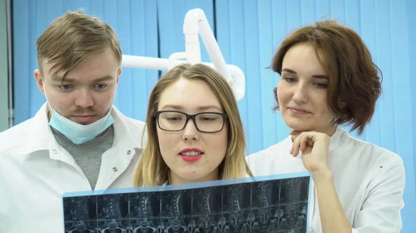 Equipa de médicos a ver imagens de ressonância magnética. Mídia. Médicos de uniforme branco assistindo RM e compartilham opiniões sobre diagnóstico — Fotografia de Stock