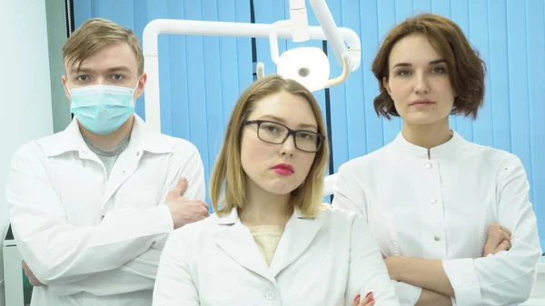 La squadra di dottori è in piedi con le mani incrociate. I media. Tre medici in uniforme bianca stanno con le braccia incrociate — Foto Stock