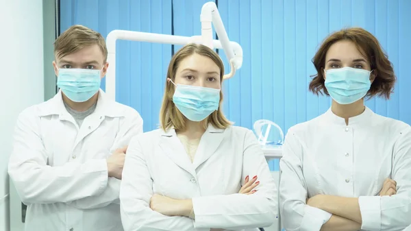 La squadra di dottori è in piedi con le mani incrociate. I media. Tre medici in uniforme bianca stanno con le braccia incrociate — Foto Stock