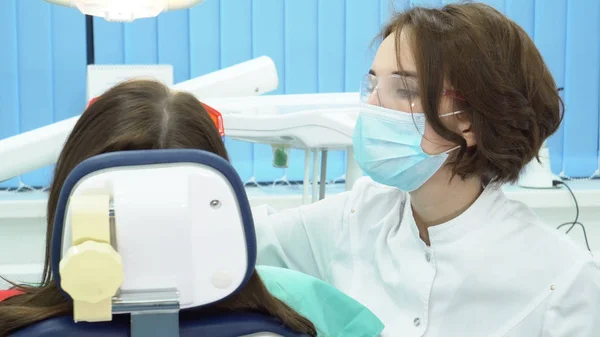 Dentista trabajando con asistente. Medios. El dentista después de trabajar con una herramienta se la da al asistente durante el procedimiento —  Fotos de Stock