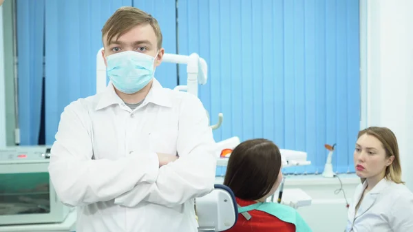 Zubní lékař konzultuje s pacientem. Média. Mužské asistent stojí v uniformě a masku na pozadí zubař diskuse o zacházení s pacientem — Stock fotografie