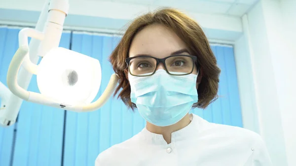 Vista inferior del dentista femenino. Medios. Atractiva mujer dentista encender lámpara electrónica examina pacientes cavidad oral —  Fotos de Stock