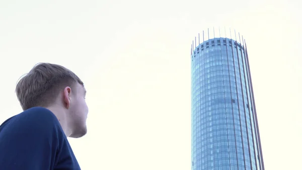 Вид на людину, що дивиться на скляну будівлю. Медіа. Чоловік стоїть і дивиться на скляний фасад сучасного офісного будинку — стокове фото