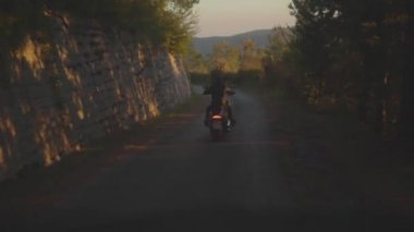 Dikiz bir adam bir motosiklet binme. Hisse senedi. Adam bir motosiklet orman asfalt yolda sürme