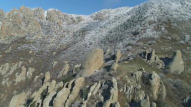 Karlı çalılar ve ağaçlar mavi gökyüzü karşı kapalı bir dağ tepe üzerinde hava görünümünü büyük kayalar. Vurdu. Kış manzarası.