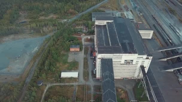 Luchtfoto van enorme grijs industrieel gebouw in de buurt van trein- en afval grond, omringd door bos. Industriële zone van boven. — Stockvideo