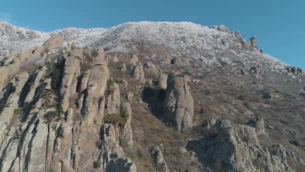 Formes énormes et bizarres de rochers de montagne entourés d'arbustes enneigés et d'arbres contre le ciel bleu. Fusillade. Gros plan . — Video