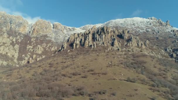 Mavi açık gökyüzü açık güneşli bir günde çalılar tarafından kaplı yeşil bir dağın üzerinde görkemli kaya oluşumu. Vurdu. Havadan görünümü. — Stok video