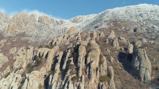 Vista aérea de la formación de rocas contra el cielo azul claro y la cima de la montaña cubierta por arbustos congelados. Le dispararon. Escalando las rocas . — Vídeos de Stock