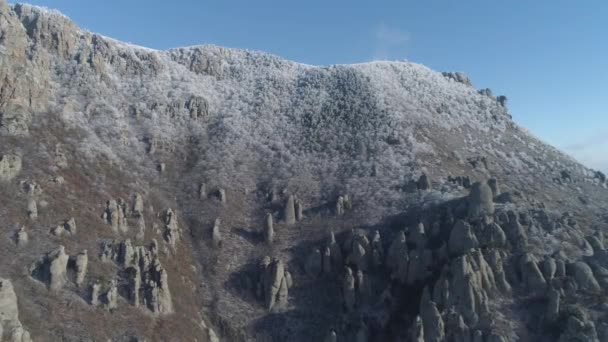 Vista en la cima de la montaña cubierto de enormes rocas y arbustos nevados contra el cielo azul claro. Le dispararon. Vista aérea . — Vídeos de Stock