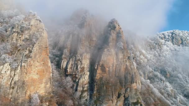 Alte Klippen in der Nähe der Bergspitze, bedeckt von gefrorenen Nadelbäumen in grauen Wolken vor blauem Himmel. Schuss. Schöne Aussicht. — Stockvideo