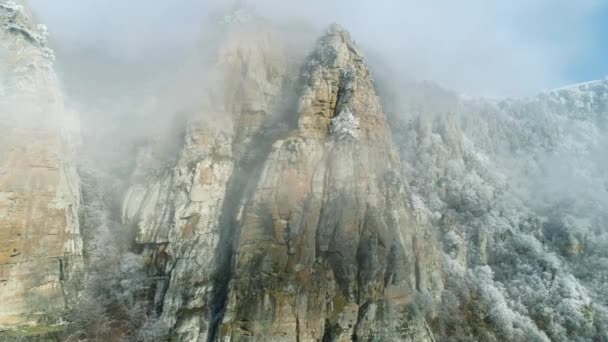 在山顶附近的旧悬崖上, 被冰冻的针叶树覆盖, 灰蒙蒙的云朵映衬着蓝天。拍摄。美丽的景色. — 图库视频影像