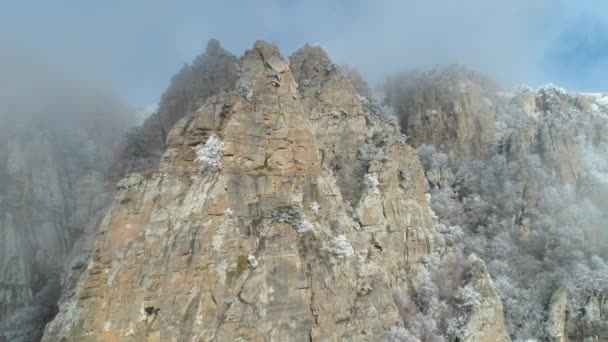 View on majestic mountain cliffs in grey clouds against blue sky, overgrown by frozen trees and shrubs. Shot. Mountain landscape. — Stock Video