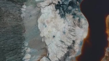 Kahverengi su ile gölet yakınındaki gri kayalık yüzeyinde hava görünümünü çiftin güzel süslü elbiseler Prenses ve robot kucaklama. Görüntüleri. Film karakterler