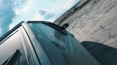 Siyah Rus araba mavi bulutlu gökyüzü karşı kumlu yüzey üzerinde hareket tarafındaki yakından görmek. Görüntüleri. Kum yarış