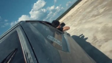 Siyah Rus araba mavi bulutlu gökyüzü karşı arabadan bakan adam ile kumlu yüzey üzerinde hareket tarafındaki yakından görmek. Görüntüleri. Kum yarış