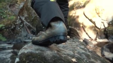 Genç adam beyaz ceket ve kauçuk güzel sonbahar ormandaki büyük taş tırmanma botlar. Görüntüleri. Yakın çekim