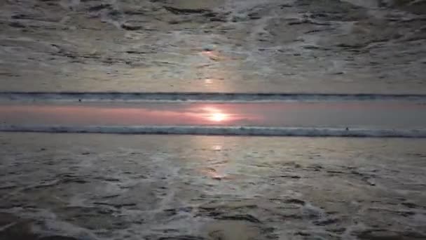 Prachtige zonsondergang hemel boven de oceaan met een spiegeleffect horizon, uitzicht vanaf de kust. Eindeloze golven en mensen in water, aanvang thema. — Stockvideo