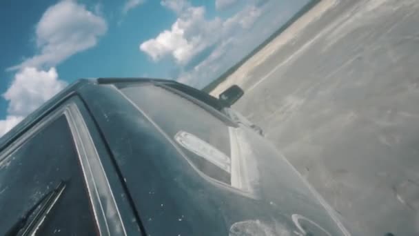 Vista de cerca desde el lado del coche negro ruso que se mueve sobre la superficie arenosa contra el cielo azul nublado. Filmación. Carreras de arena — Vídeo de stock