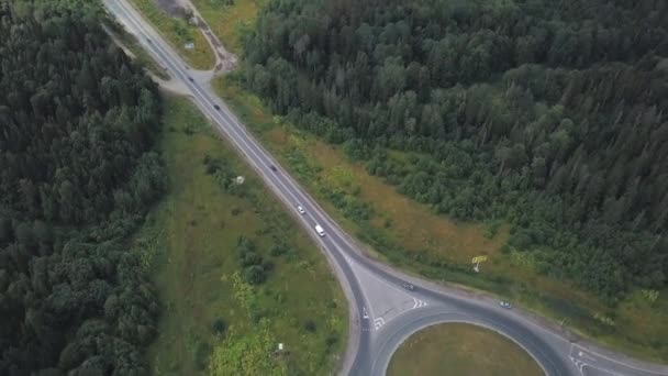 Круглый круг с движущимися машинами возле леса на загородной трассе. Клип. Вид с воздуха — стоковое видео