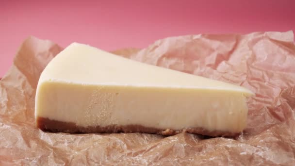 La perte d'une tranche de gâteau au fromage frais traditionnel sur un papier d'emballage alimentaire. Cadre. Isolé sur rose — Video