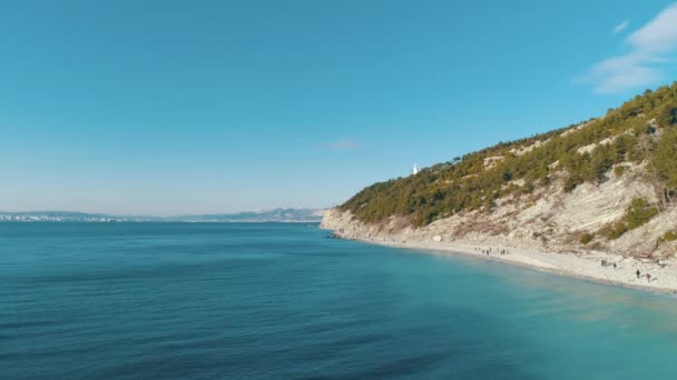 Вид з повітря на горбисте узбережжя і бірюзово чиста морська вода в сонячний день. Постріл. Красивий морський пейзаж — стокове відео