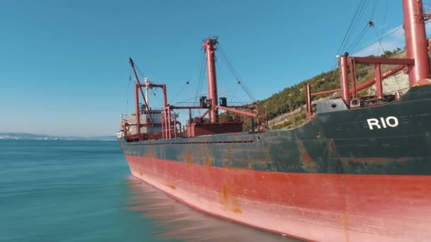 Close-up van grote rode vrachtschip op het dok in de buurt van de kust. Schot. Zee vervoer — Stockvideo