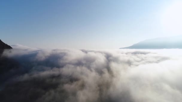 Wunderschöner Sonnenaufgang über den Wolken, Blick von der Bergspitze. Schuss. Antenne für langsame Bewegung dicker Wolken vor blauem Himmel und strahlender Sonne. — Stockvideo