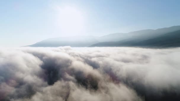 Beautiful endless heaven, bright sun and blue, clear sky. Shot. Breathtaking view of white clouds flowing against mountain tops and blue sky in the morning. — Stock Video