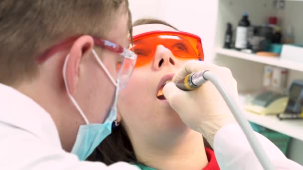 Vista de cerca del dentista en guantes de látex examinar a la mujer con la boca abierta, concepto de cuidado dental. Medios. Espalda de un dentista que trata los dientes de una paciente joven . — Vídeos de Stock