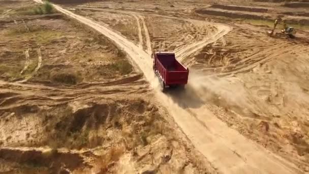 Vrachtwagen rijdt op zand steengroeve weg. Scène. Bovenaanzicht van dump truck rijden op gele onverharde weg in platteland. Grote vrachtwagens op bouw of steengroeve terrein — Stockvideo