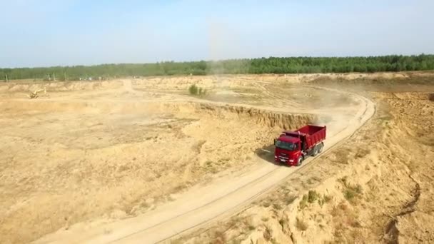 Самоскид їзди по сільській дорозі. Сцена. Вид зверху вантажівка їде, залишаючи пір'я пилу в грунтової дороги в сільській місцевості на фоні екскаватор кар'єри — стокове відео