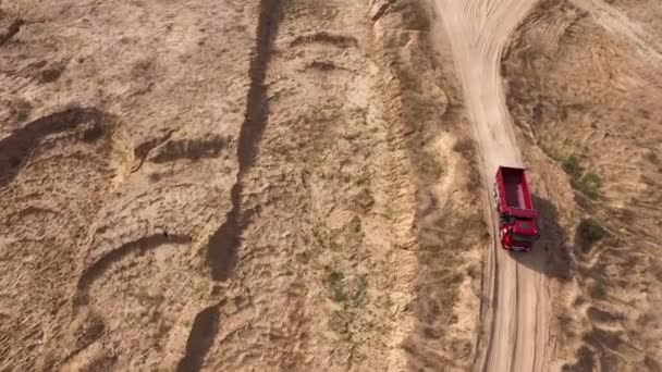 Vista dall'alto di camion guida su strada rurale. Scena. Dump truck cavalca sulla strada cava giallo secco in estate. Macchine pesanti su strade di costruzione e cava — Video Stock