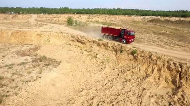 Vrachtwagen rijdt op klei weg. Scène. Bovenaanzicht van dump truck rijden op droge klei weg steengroeve op achtergrond van bosgebied — Stockvideo