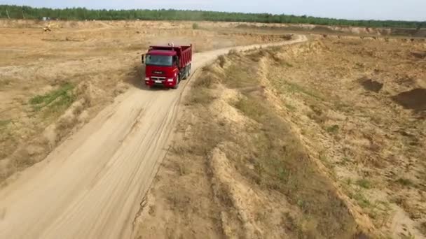 Kipper open kuil onderweg. Scène. Bovenaanzicht van dump truck rijden op klei weg groeve in de natuur met bos op horizon — Stockvideo