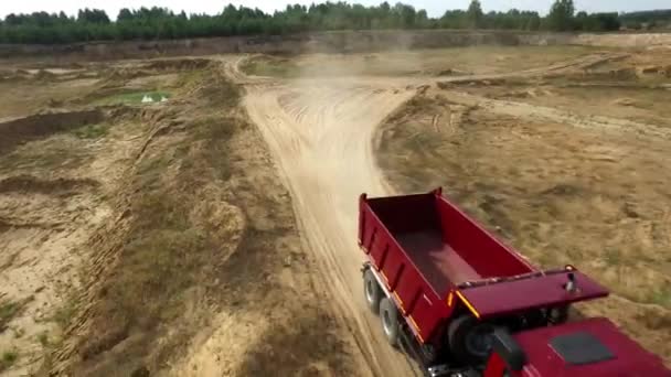 トラックはほこりっぽい道に乗って.シーン。ほこりの証跡を残し露天掘りの粘土の未舗装の道路上を運転するダンプ トラックのトップ ビュー — ストック動画