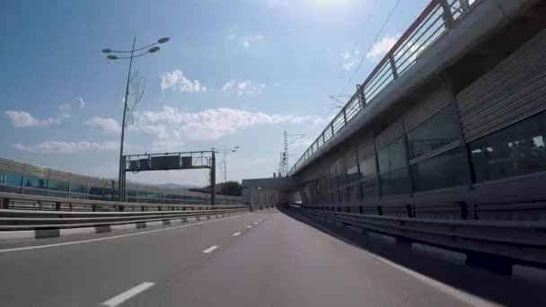 Vista desde el coche en la carretera suburbana con puentes. Escena. Hermoso paisaje con suburbio de carretera de asfalto, pasando por debajo de puentes con vistas al cielo azul — Vídeo de stock