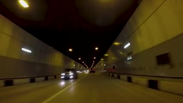 O carro anda no túnel de asfalto. Cena. Bela paisagem urbana de novo túnel rodoviário com tráfego em luz de lanternas amarelas — Vídeo de Stock