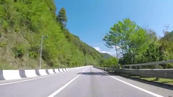 Автомобільні прогулянки по гірській асфальтовій дорозі з лісом. Сцена. Сільське шосе в гірській місцевості з трафіком і красивим пейзажем з зеленню і блакитним небом — стокове відео