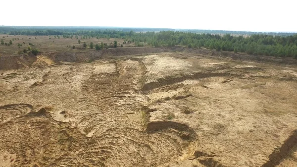 Піщаний кар'єр у сільській місцевості. Сцена. Вид зверху на порожній жовтий кар'єр з дорогами та ямами на фоні зелені та лісової зони влітку — стокове фото