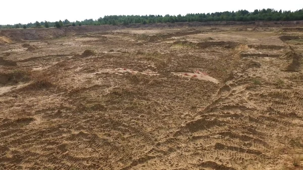 Піщаний кар'єр у сільській місцевості. Сцена. Вид зверху на порожній жовтий кар'єр з дорогами та ямами на фоні зелені та лісової зони влітку — стокове фото