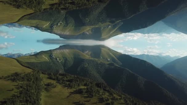 Veduta aerea delle grandi montagne coperte di erba verde e alberi contro il cielo blu e nuvoloso con effetto specchio astratto. Gli hanno sparato. Riflessione astratta — Video Stock