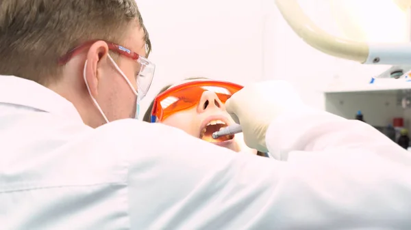 Close up view of dentist in latex gloves examining woman with opened mouth, dental care concept. Media. Back of a dentist who treats teeth of young woman patient.