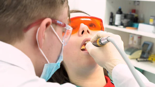 Close-up van tandarts in latex handschoenen vrouw met geopende mond, tandheelkundige zorg concept te onderzoeken. Media. Achterzijde van een tandarts die tanden van jonge vrouw patiënt behandelt. — Stockfoto