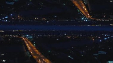Arabalar ve şehrin gece ışık, ayna ufuk etkisi ile hareketli bir dere Köprüsü hava gece manzarası. Medya. Gece şehir ve köprü manzara Nehri, kurulduğu günden bu tema çarpıcı.